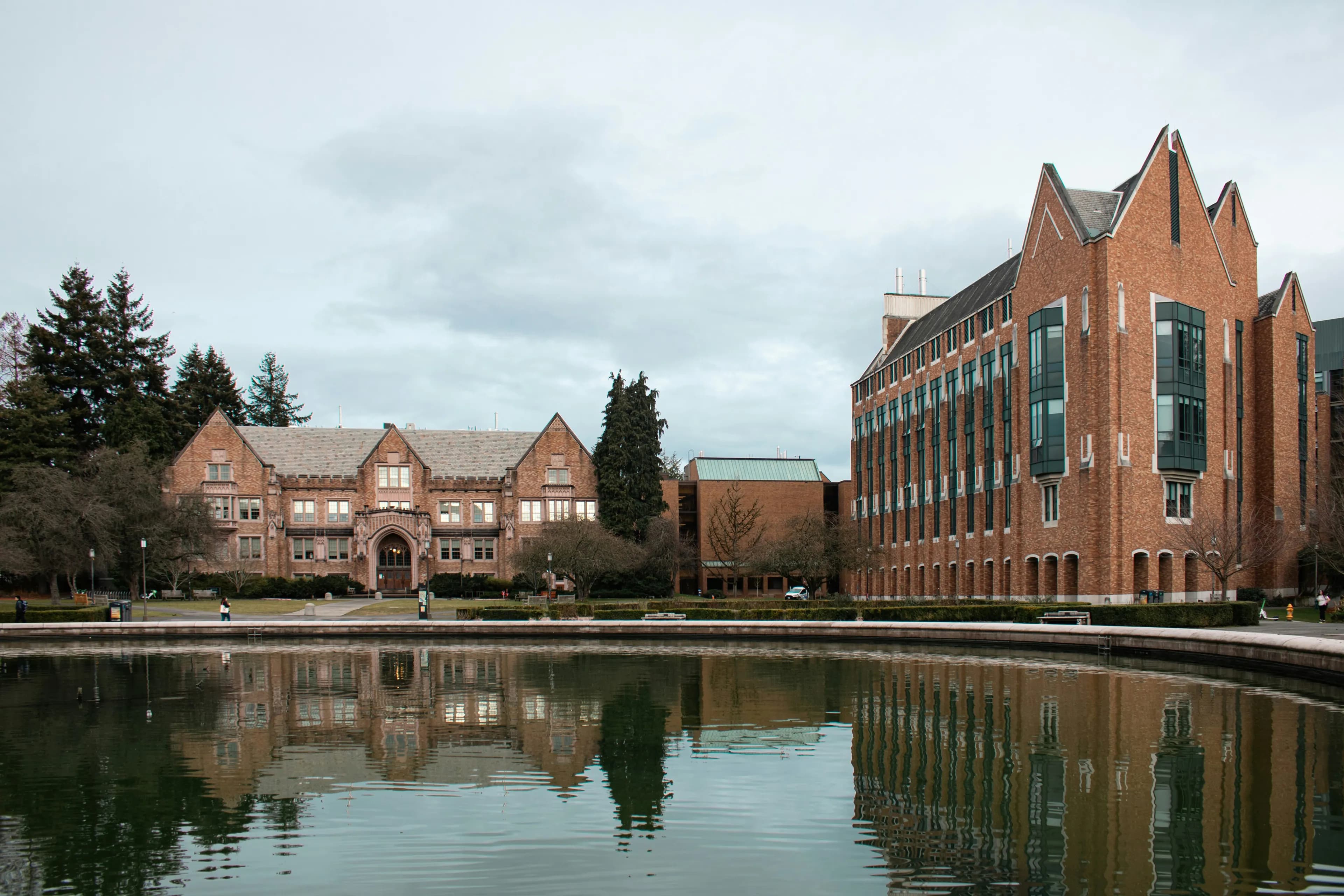 Brick halls of the University of Washington reflected in Drumheller Fountain on an overcast day.